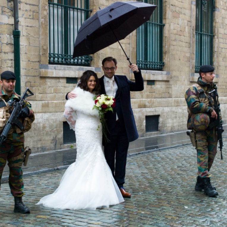 Brussels Belgium 21 November 2015. Terror alert level for Brussels was put at 4, the maximum on a scale of 1 to 4. There is "a very concrete and imminent threat".These Greek-Flemish newly weds got married and have a portrait made with the military posing for their special marriage day. Bride Konstantina Karadimitropoulou and groom Roeland Lacroix holding umbrella